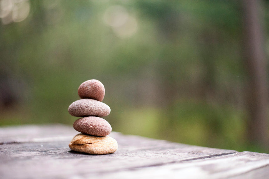 Stack of stones on a wooden surface with a blurred natural background